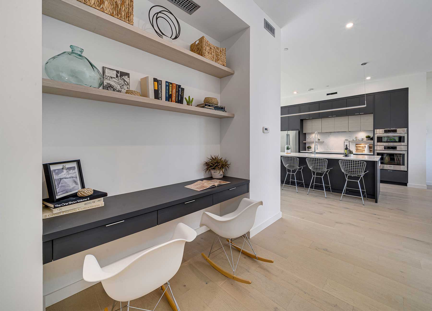 An office nook beside a modern kitchen inside a luxury high-performance home.